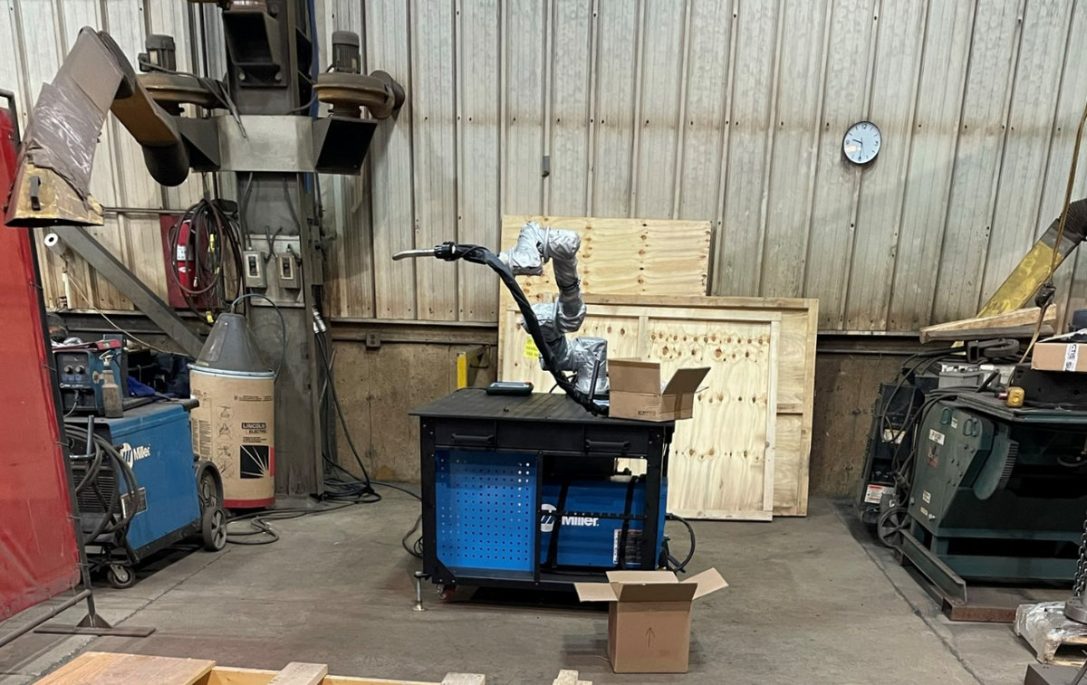 Assembled Robotic Welding Arm attached to a tooling table waits for material to be loaded to begin welding. 